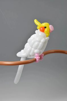 a plastic bird sitting on top of a wooden branch