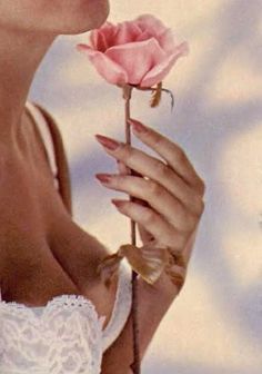 a woman holding a pink rose in her right hand