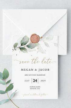 save the date card with greenery and gold foil on it, sitting next to an envelope