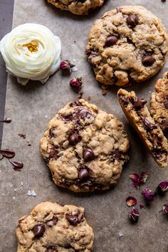 chocolate chip cookies with white frosting and dried flowers on a piece of parchment paper