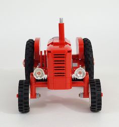 a red toy tractor sitting on top of a white table