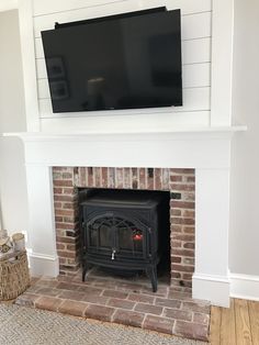 a fireplace with a flat screen tv mounted above it and a basket on the floor