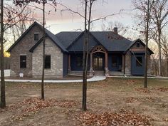 a house in the woods with lots of leaves on the ground and trees around it