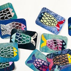 colorful fish painted on glass coasters sitting on a table