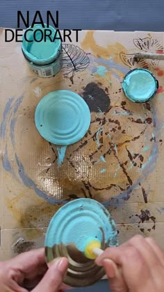 a person is painting on a piece of wood with blue paint and yellow brushes