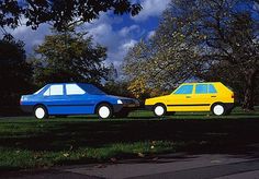 two cars are parked in the grass next to each other, one yellow and one blue