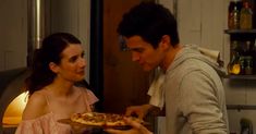 a man holding a pizza in front of a woman