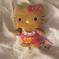 a hello kitty stuffed animal laying on top of a white bed sheet with a tag in it's ear