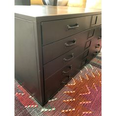 a black dresser sitting on top of a colorful rug