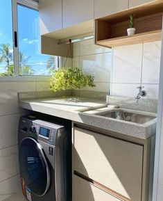 a washer and dryer in a small kitchen with an ocean view out the window