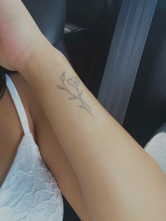 a woman with a tattoo on her arm sitting in the back seat of a car