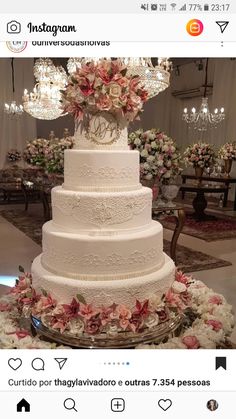 a white wedding cake sitting on top of a table next to flowers and chandeliers