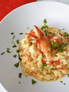 a white plate topped with riso and shrimp on top of rice covered in garnish