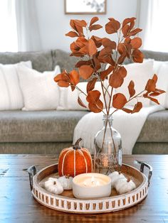 a glass vase filled with flowers and candles on top of a wooden table next to a couch