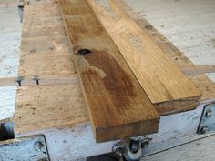 a wooden bench sitting on top of a floor next to some metal brackets and wood planks