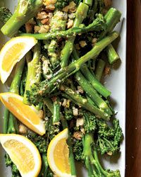 broccoli and asparagus with lemon wedges on a white platter