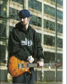 a man holding a guitar in front of a building