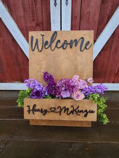 a welcome sign with purple and pink flowers in front of a barn door that reads,'welcome harry '