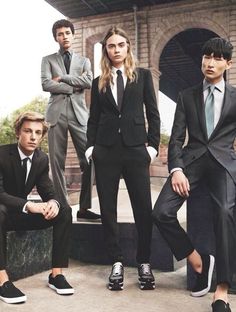 three men in suits and ties are posing for a photo with one man sitting on the ground