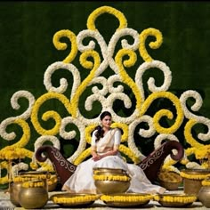 a woman sitting on top of a golden bowl next to two vases filled with flowers