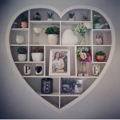 a heart shaped shelf filled with pictures and flowers