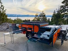 an orange and black utility vehicle parked on the side of a road next to trees