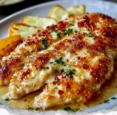 a white plate topped with chicken covered in sauce next to french fries and potato wedges