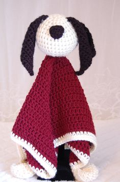 a crocheted dog is wearing a red and white blanket