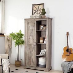 a living room with a guitar on the floor and a book shelf in front of it