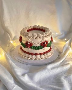 a three layer cake with white frosting and red flowers