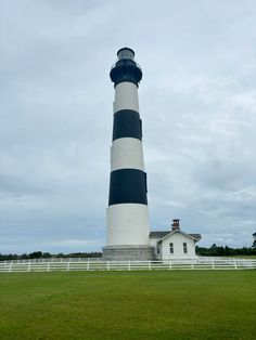 a large black and white lighthouse sitting on top of a lush green field