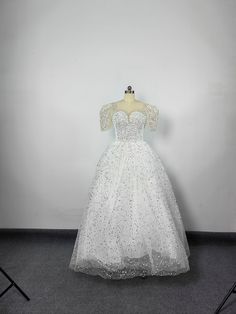 a white wedding dress on display in front of a wall