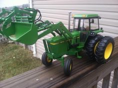 a toy tractor is parked on the back of a wooden fence next to a house