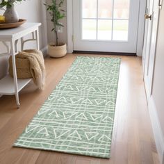 a green rug on the floor in front of a white door with a potted plant next to it