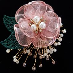 a pink flower with pearls and green leaves