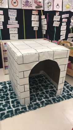 a small white dog house made out of cardboard on top of a blue area rug