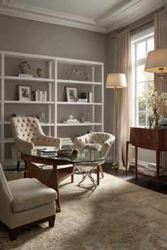 a living room with two chairs and a table in front of a book shelf filled with books