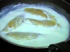 three fish frying in a pan with milk and sauce on the stove burner