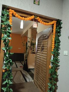 an entry way decorated with orange flowers and greenery on the door frame is shown