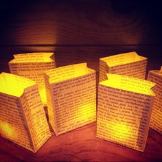 several small books are lit up with paper lights on the table in front of them