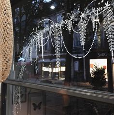 a store window decorated with christmas lights and snowflakes on the windows sill