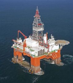 an orange and white oil rig in the middle of the ocean with water around it