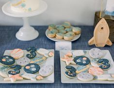 two plates with cookies on them sitting on a table next to other desserts and pastries