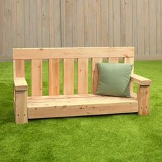 a wooden bench sitting on top of a lush green grass covered field next to a fence