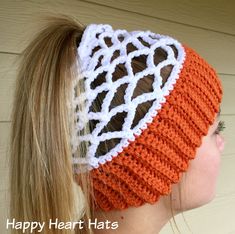 a woman wearing an orange and white knitted headband with the words happy heart hats on it