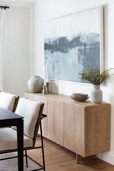 a dining room table with chairs and a painting on the wall