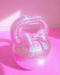 a shiny pink kettle with a bow on the front and side, against a bright pink background