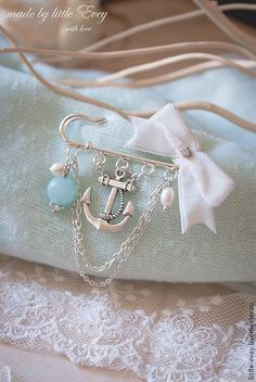 an anchor and chain necklace on top of a blue pillow with white lace around it