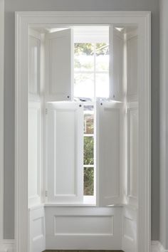 an open window with white shutters and wood flooring