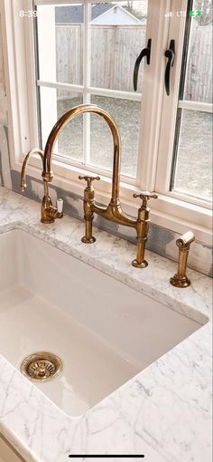 a white sink sitting under a window next to a faucet